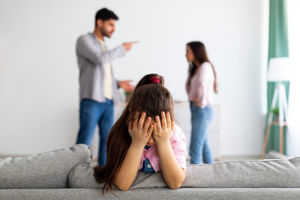 Crisis. Little Girl Crying, Closing Face With Hands While Her Angry Parents Fighting on the Background Black and family